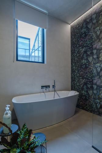a white bath tub in a bathroom with a window at The Hide in Ghent