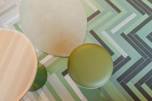 a table with two green chairs on a geometric floor at The Hide in Ghent
