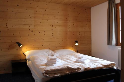 a bed in a room with a wooden wall at Hotel Wynegg in Klosters