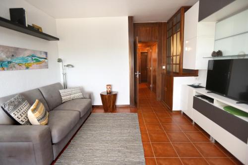 a living room with a couch and a flat screen tv at Like-home-T1 Apt-Sea View, near the beach in Carcavelos