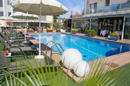 einen Pool mit Stühlen und einem Sonnenschirm in der Unterkunft Best Western Hotel Mediterraneo in Castelldefels