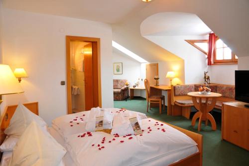 a bedroom with a bed with red rose petals on it at Hotel Zum Goldenen Hirschen in Freistadt