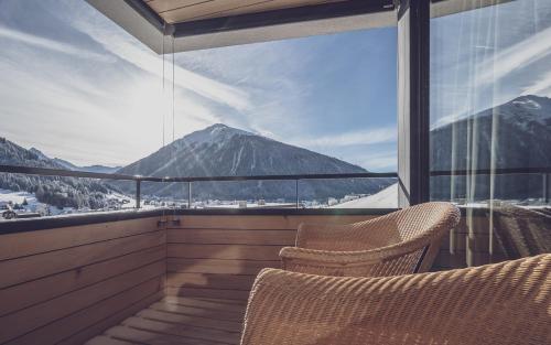 a balcony with two chairs and a view of a mountain at Parsenn Resort in Davos