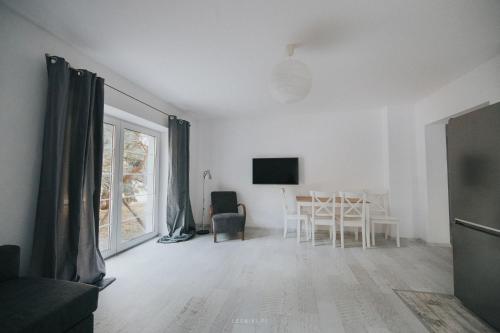 a white living room with a table and a tv at Leśniki in Babimost