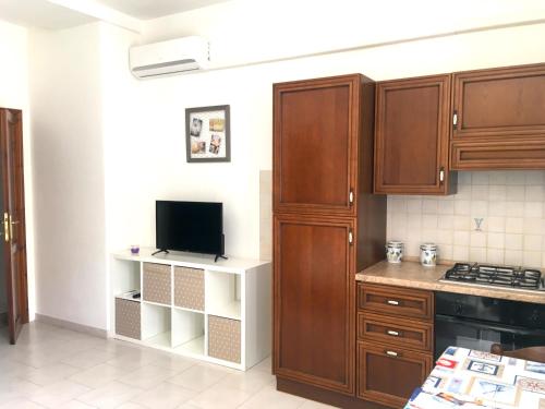 cocina con armarios de madera y TV. en Apartment Maria en Tergu