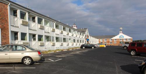 a parking lot with cars parked in front of a building at Ocean Club on Smuggler's Beach in South Yarmouth