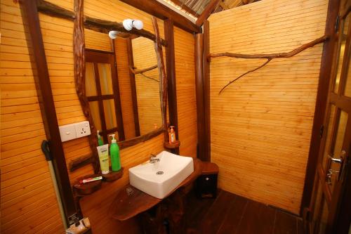 a bathroom with a sink and a wooden wall at Go Yala Farm Villa in Tissamaharama