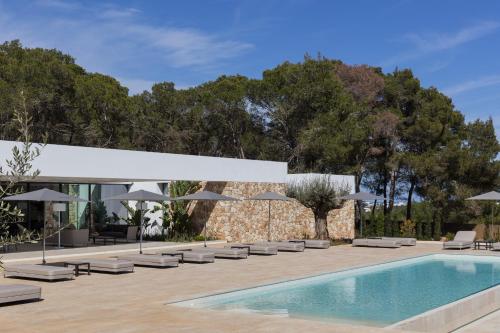 uma piscina com espreguiçadeiras e guarda-sóis num pátio em Villa Calma em Sant Llorenç de Balafia