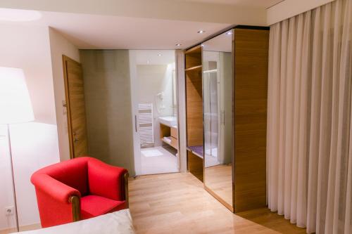 a room with a red chair and a mirror at Schlosstaverne Thannhausen in Weiz