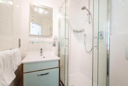 ein weißes Bad mit einem Waschbecken und einer Dusche in der Unterkunft Hotel Haus Appel in Rech