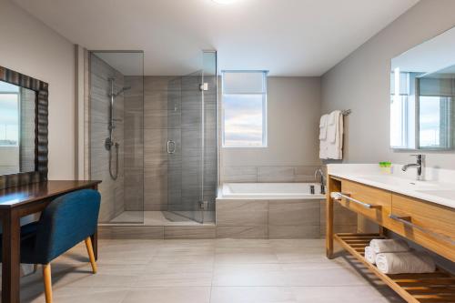 La salle de bains est pourvue d'une douche, d'un lavabo et d'une baignoire. dans l'établissement Imperia Hôtel et Suites Boucherville, à Boucherville