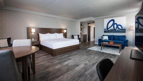 a hotel room with a bed and a blue couch at Imperia Hôtel et Suites Boucherville in Boucherville