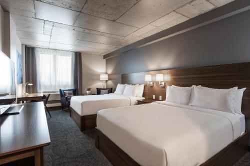 a hotel room with two beds and a desk at Imperia Hôtel et Suites Boucherville in Boucherville
