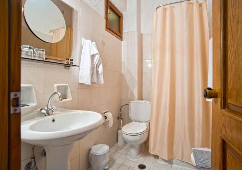ein Badezimmer mit einem Waschbecken, einem WC und einem Spiegel in der Unterkunft Olympic Hotel in Delphi