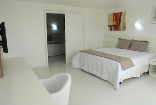 a white bedroom with a bed and a chair at GOLD MARTAN HOTEL in Belém