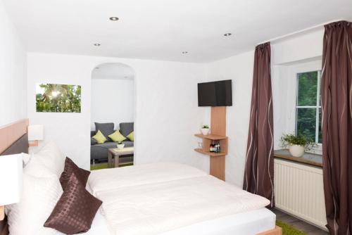 1 dormitorio con cama blanca y sofá en Hotel Garni BURG WALDENSTEIN, en Rudersberg