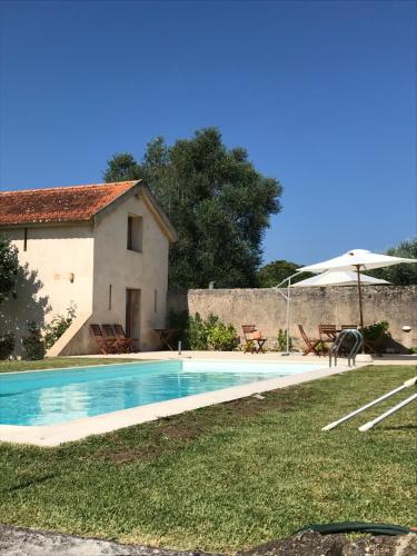 a pool in front of a house with an umbrella at ADOBE TYPICAL COTTAGE in AlpalhÃ£o
