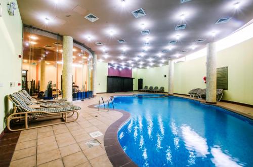 Karan Sharq for Hotel Apartment في الجبيل: مسبح في غرفة الفندق مع كراسي للاستلقاء ومسبح