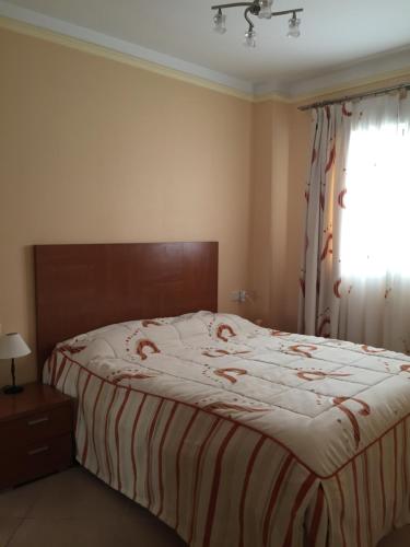 een slaapkamer met een bed met een gestreepte deken en een raam bij Apartment Costa Formentera in Formentera de Segura