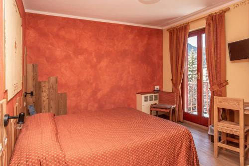 a bedroom with a bed with an orange bedspread at Hotel Chaberton in Cesana Torinese