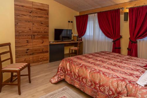 a bedroom with a bed and a tv and red curtains at Hotel Chaberton in Cesana Torinese