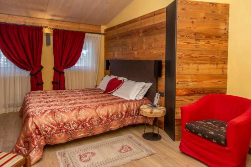 a bedroom with a bed and a red chair at Hotel Chaberton in Cesana Torinese
