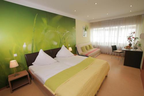 ein Schlafzimmer mit einem großen Bett und einer grünen Wand in der Unterkunft Gasthof Wimmer Weissbräu in Simbach am Inn