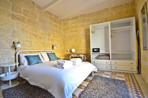 sypialnia z łóżkiem i kamienną ścianą w obiekcie Eight Point Living 6B w mieście Birgu
