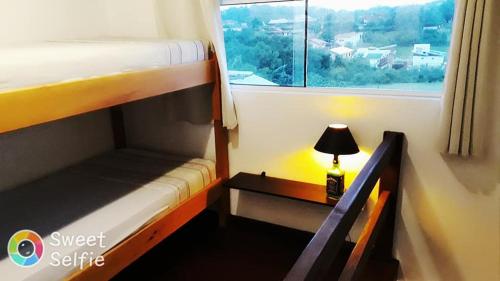 a bedroom with two bunk beds and a table with a lamp at Pousada Morrison in Praia do Rosa