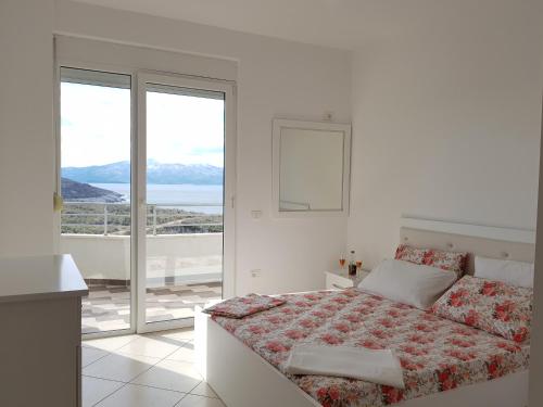 a white bedroom with a bed and a balcony at Exotic Apartment in Sarandë