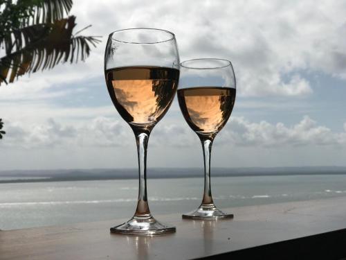 two glasses of wine sitting on a table near the ocean at Bangalô dos Sonhos in Morro de São Paulo