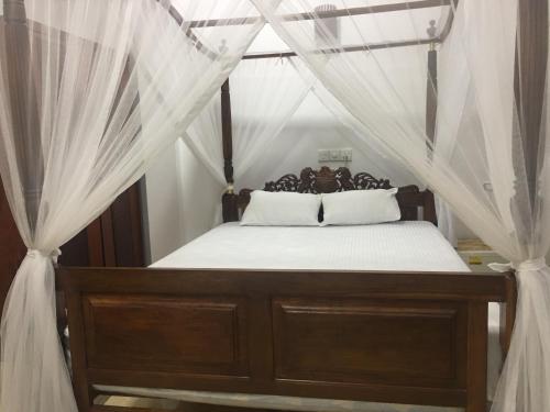 a bedroom with a canopy bed with white drapes at Villa N in Unawatuna