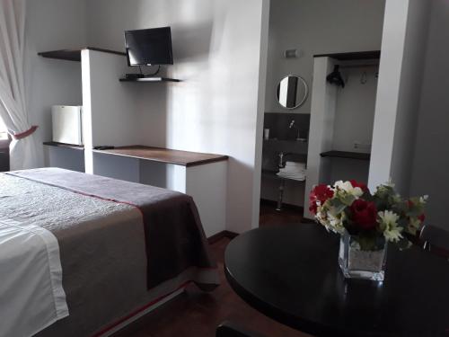 a room with a bed and a table with a vase of flowers at Pousada Narinari in Bombinhas