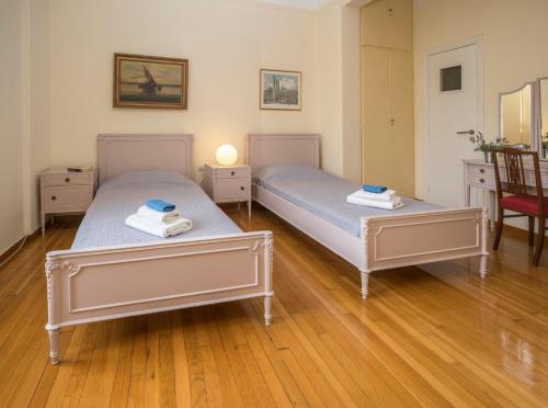 two beds in a room with wooden floors at ACROPOLIS MUSEUM APARTMENT in Athens