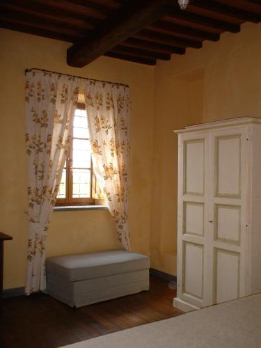 a bedroom with a window and a bench next to a door at Le Fonti A San Giorgio in Montespertoli