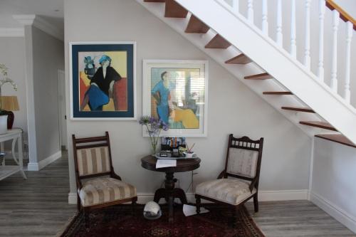 a living room with two chairs and a table and stairs at Sandals Guest House in Durban