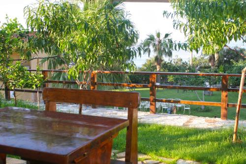 a wooden bench sitting in the grass next to a fence at Villa Paladino - B&B e Guest House in Scilla