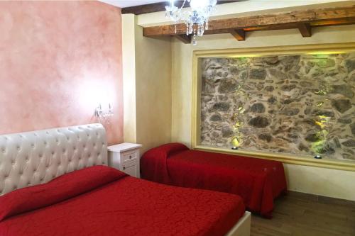 a bedroom with a red bed and a stone wall at Villa Paladino - B&B e Guest House in Scilla