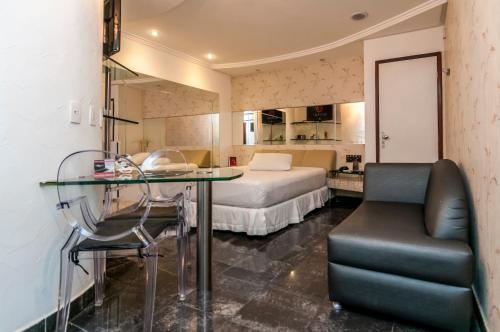 Trópicos Motel في ناتال: غرفة نوم بسرير وطاولة زجاجية وكرسي