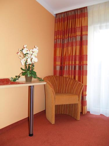 a chair and a table with a vase of flowers at Tirolerhof in Lermoos