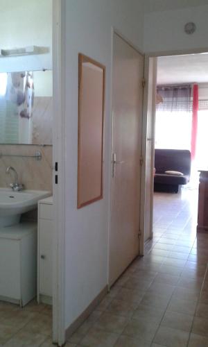 La salle de bains est pourvue d'un lavabo et d'une porte avec un miroir. dans l'établissement 84 Rue du Vieux Village, à Carnon-Plage