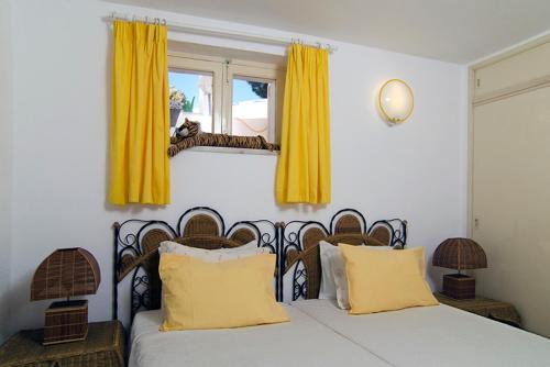 a bedroom with a bed with yellow curtains and a window at Vila Monte Luz in Ferragudo