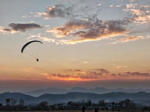 a person is flying a parachute in the sunset at The Bunker Bir in Bīr