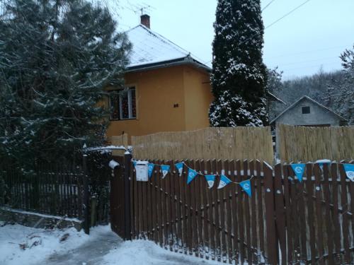 una cerca frente a una casa en la nieve en Tóth Apartman en Telkibánya