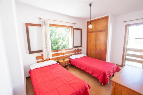 two beds in a room with red sheets at Bosc i Sol VT in Es Calo