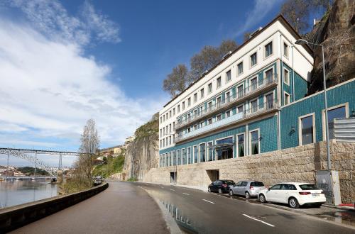 a large building with cars parked next to a river at Eurostars Porto Douro in Porto