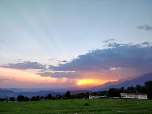 a sunset in a field with the sun setting at The Bunker Bir in Bīr