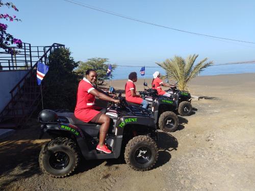 three people riding on atvs on the beach at Edificio Magico in Tarrafal