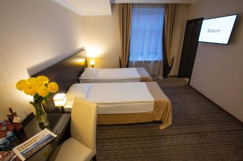 a hotel room with two beds and a flat screen tv at Optima Cherkasy Hotel in Cherkasy