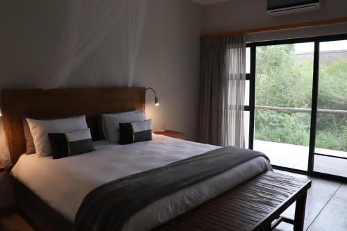 a bedroom with a large bed and a large window at MANZINI RIVER HOUSE - Mjejane Private Game Reserve, Greater Kruger National Park in Hectorspruit